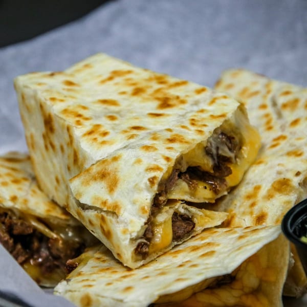 Close-up of golden-brown quesadilla triangles filled with melted cheese and savory meat from Cabo Taco.