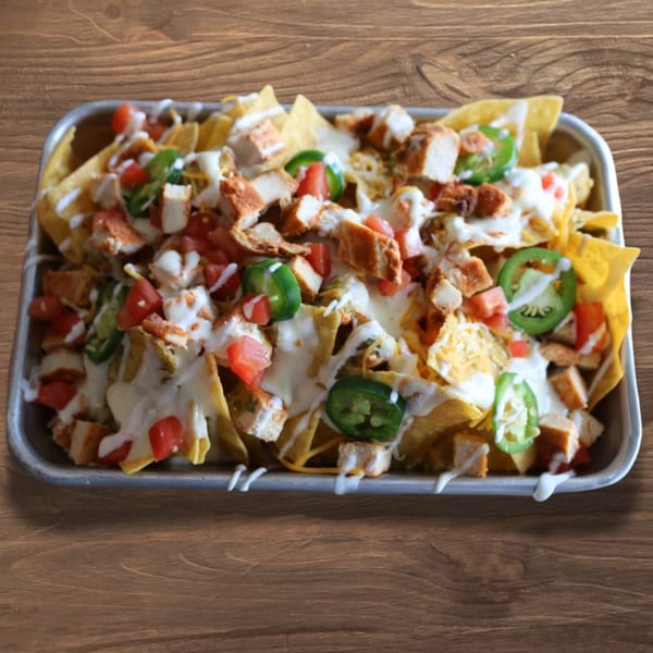 Cabo Taco's chicken nachos with melted cheese, diced tomatoes, jalapeños, and sour cream drizzle.