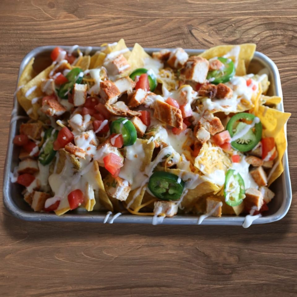 Cabo Taco's chicken nachos with melted cheese, diced tomatoes, jalapeños, and sour cream drizzle.