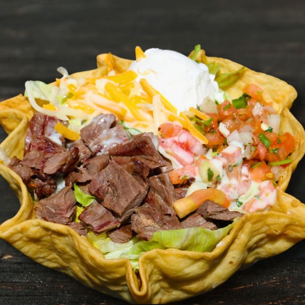 Cabo Taco's taco salad with steak, lettuce, cheese, pico de gallo, and sour cream in a fried tortilla bowl.